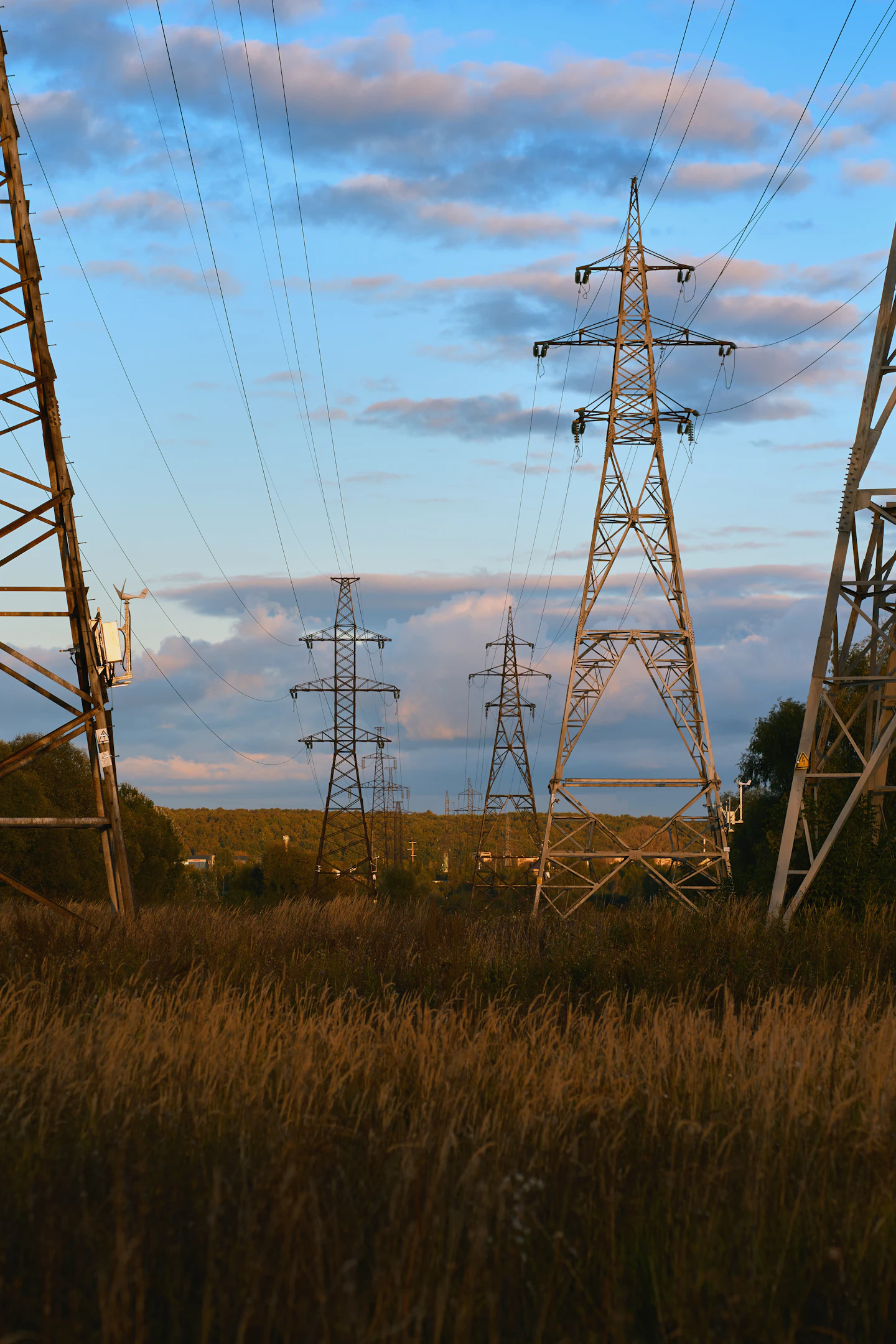 High-voltage transmission lines crossing a field at sunset