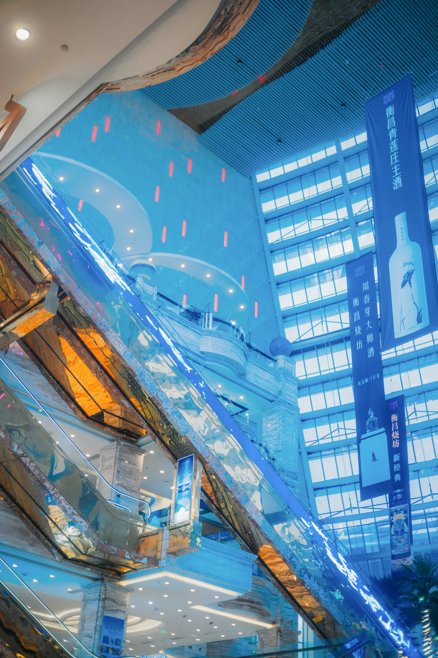 Modern shopping-center atrium with escalators and retail banners